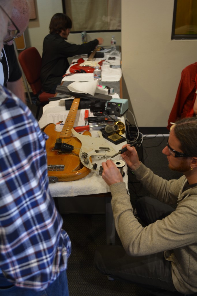 Ryan soldering the electronics on a bass